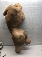 Overall view of the wall-mounted torso sculpture showing full form and patina