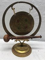 Full view of the brass gong with stand and wooden mallet, showing the overall set and condition including visible crack on the gong's top circle.