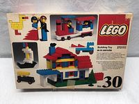 Front of sealed vintage Lego Universal Building Set No. 30 box showing multiple build examples including house with red roof, train cars, figures, and a duck build.