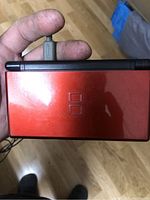 Top closed view of red Nintendo DS Lite handheld showing glossy finish.