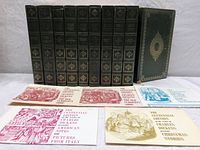 All 10 volumes of Charles Dickens' hard cover set lined up with inserted illustrated paper pamphlets in front