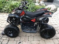 Side view of black and red electric quad showing body, seat, tires