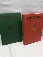 Two hardcover books, one red and one green, standing upright showing front cover titles and gold emblem.