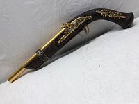 Full view of the wooden and brass flintlock decorative prop showing the curved stock and brass barrel.