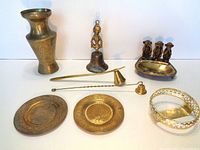 Photo of all brass items including vase, bell, plates, trays, ramrod, pitcher, and figurines.