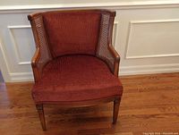 Front view of wood frame chair with burnt orange/brown upholstery and cane side panels