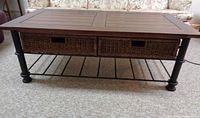 Front view of full coffee table showing wood top, wicker drawers and metal frame