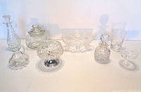 Group photo showing the full collection of crystal and glassware items including a square-shaped jar, small decanter, pedestal bowl, glass pitcher, tumblers, and small dishes.