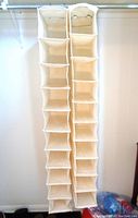 Two beige fabric hanging shoe organizers hanging on a closet bar, each with 10 compartments visible vertically.