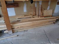 Wide angle showing stacked lumber pieces against a wall with various lengths and widths