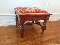 Side angle showing detailed turned wooden legs and patterned upholstered top of the stool.