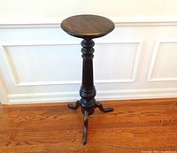Full view of the wooden plant stand showing the round top, turned column, and tripod leg base.