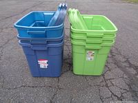 Photo showing three stacked blue storage totes and three stacked green storage totes outdoors on pavement.