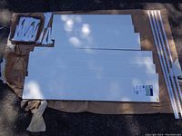 Photo shows six white wooden shelves laid out on a cloth. Three longer shelves measure about 4 ft x 8 in and three shorter shelves measure about 3 ft x 8 in. White mounting brackets and metal wall tracks are placed alongside the shelves.