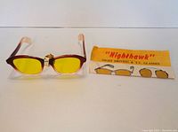 Vintage Nighthawk glasses with yellow lenses and original informational insert on a white background.