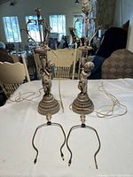 Pair of statuesque cherub lamps placed on a table, showing full height and wiring.