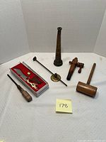 Full lot of antique fire hose nozzle and assorted tools arranged on white surface.