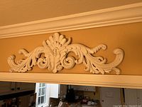 Front view of the white decorative carved wall plaque mounted on wall.