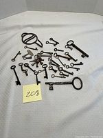 Wide shot showing full collection of 28 antique keys laid on a white textured surface