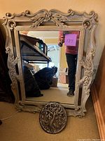 Front view of large rectangular mirror with ornate wood frame showing carved scroll and leaf details