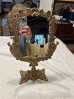 Front view of gold ornate swivel mirror with detailed frame and reflective surface