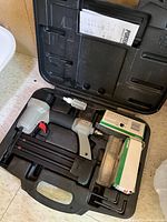 Porter-Cable brad nailer in carrying case with accessories and manuals.