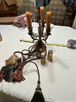 Full view showing candelabra with candles, twisted hanging cords with tassels, salt and pepper shakers, and faux pear on table.