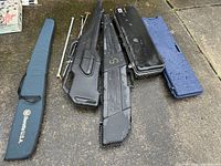 Overview image showing six cases on a wet pavement, including three black hard cases, one blue soft Beretta case, and two longer gun cases.