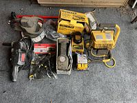 Photo showing various tools including Dewalt electric sander or polisher, handheld rotary tool, boxed accessories, and a large yellow metal-framed halogen work light on floor.
