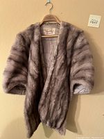 Front view of the gray mink fur coat hanging on a wooden hanger, showing the overall condition and length.