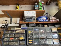 Shelves with assorted small containers, cans, and plastic drawers filled with various hardware items and garage chemicals.