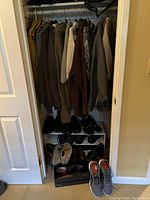 Full closet view showing hanging clothes and shoes organized on shelves and floor.