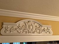 Wide view of the white decorative wall plaque showing overall ornate floral design and shape.