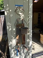 Metal person-shaped wall planter mounted on exterior wall, showing full height and rust patina.