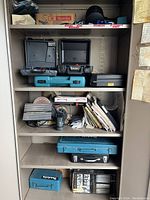 Wide shot of metal cabinet contents: toolboxes, cases, books, and accessories.