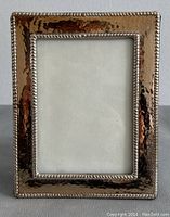 Front view of rectangular silver photo frame showing hammered texture and beaded border around the photo opening. The surface reflects light unevenly due to the hammered finish.