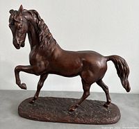 Side view showing the prancing horse sculpture with raised front leg and detailed mane and tail.