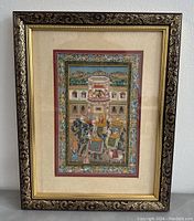 Full view of the framed Indian miniature painting showing the ornate wooden frame, beige matting, and detailed artwork of an elephant procession in front of a palace.