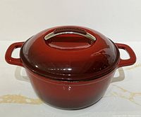 KitchenAid cast iron enamel Dutch oven roaster with lid, showing full exterior with handles and lid handle clearly visible with KitchenAid branding.