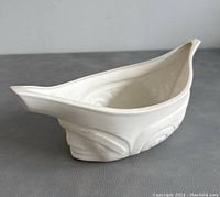 Side view of the white translucent porcelain vessel shaped as a canoe, showing the smooth interior and subtle surface details.