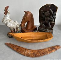 Full view of the five items: painted rooster figurine, wooden horse head sculpture, Indian God wood carving, wooden boat model, and wooden boomerang
