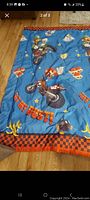 Blue kids blanket laid out, showing Mario and Luigi riding motorbikes and surrounding design elements like banana peels and stars.