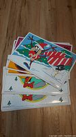 Stack of Looney Tunes placemats with one showing a character wearing a Santa hat and antlers next to a candy cane-striped object and Christmas tree.