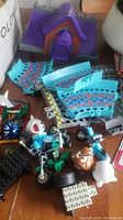Overview of building components including curved blue track pieces, character figures (Goomba, Boo, etc.), and a green rider on a motorbike toy.