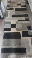 Full view of the carpet runner placed in a hallway or kitchen area on wooden flooring showing overall geometric pattern.