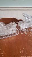 Clear crystal glass decorative sled and two crystal reindeer on wooden surface.