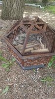 Full view of the rusted metal firepit with diamond-patterned wire mesh cover, showcasing its shape and wire panel design.