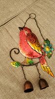 Photo of colorful metal robin bird attached to a metal swirl branch with green leaves and a blue flower, two small bells hanging from chains below