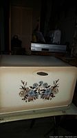 Front of the vintage metal bread box showing floral pattern on cream background