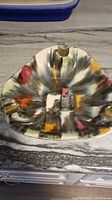 Top down view of a triangular shaped ashtray with three gold accents on cigarette rests and abstract multicolor glaze including black, orange, yellow, pink, and white.